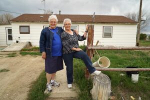 Ruth and Jane in front of a house made from a barrack that their family lived in. 